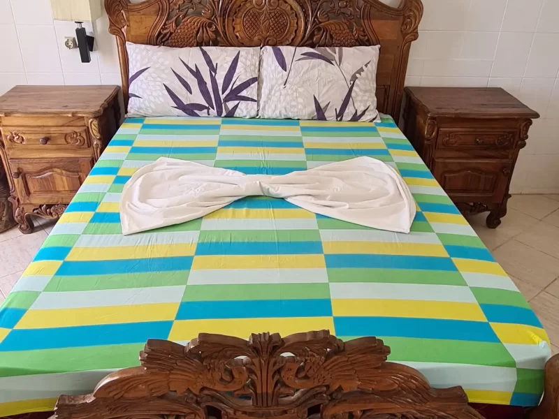 Ornate wooden bed with intricately carved headboard and footboard in Beachfront Apartment in Taghazout bedroom.