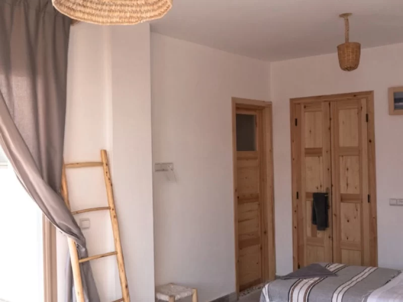 Deluxe twin room at Blue Mind Morocco showing beds, wooden doors, ladder, and woven ceiling lights.