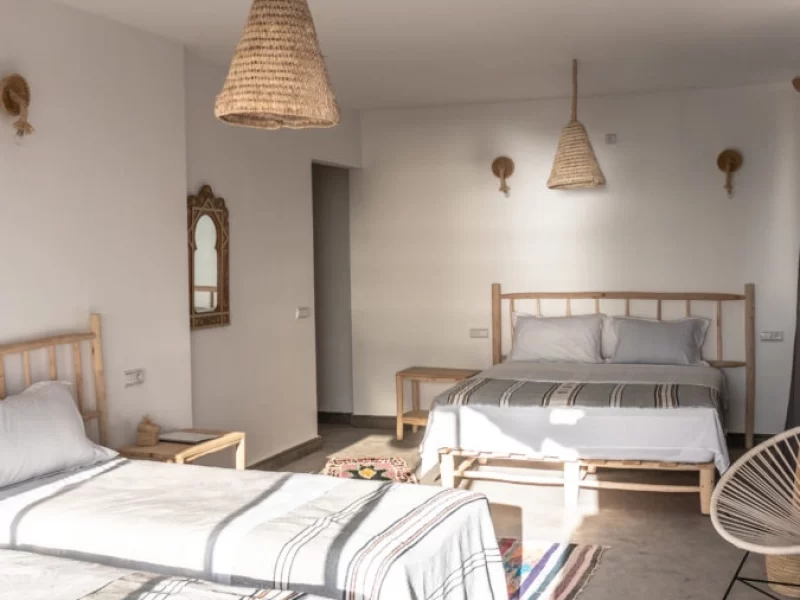 Family Suite bedroom at Blue Mind Morocco in Taghazout with multiple single beds, wooden furniture, and woven cone pendant lights.
