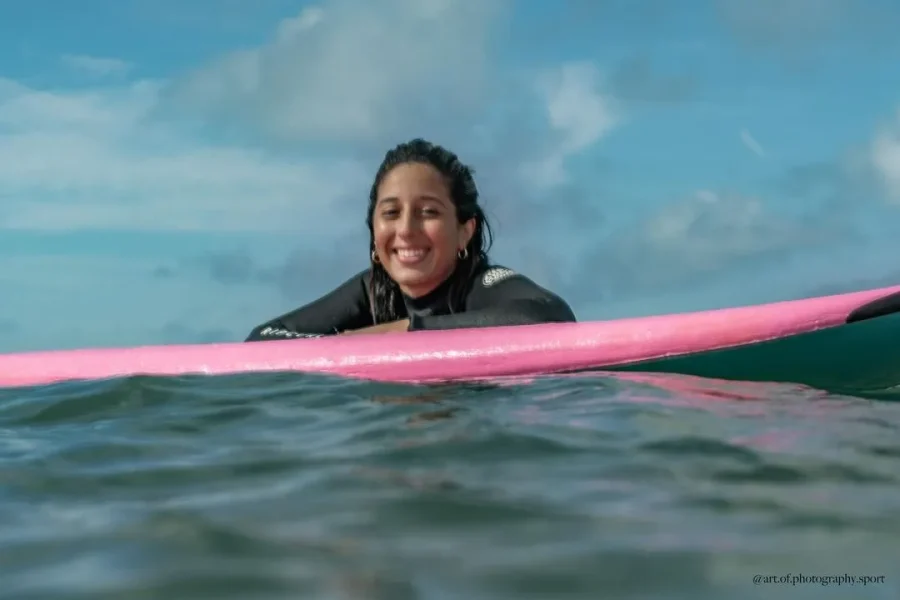 A surfer in a black wetsuit holds a pink surfboard while in the water at Bouznika, Casablanca.