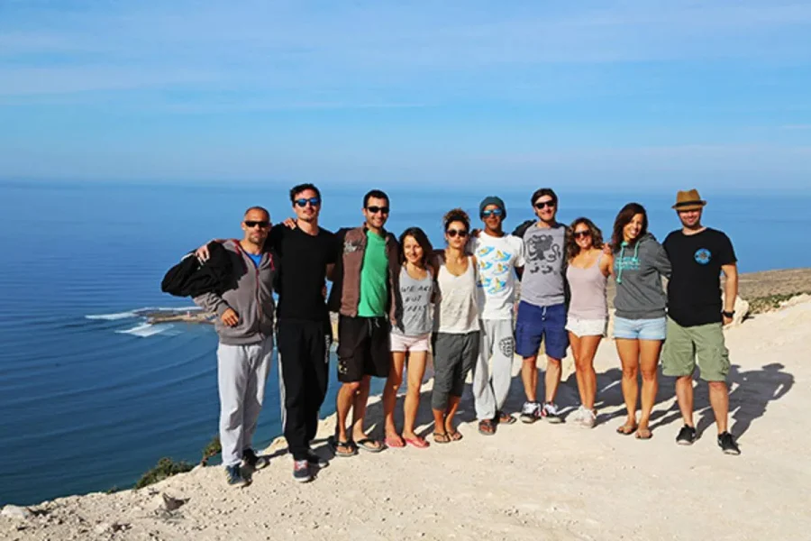 Gruppe von 11 Personen posiert gemeinsam auf einer Klippe mit Blick auf die marokkanische Küste in der Nähe von Imsouane.