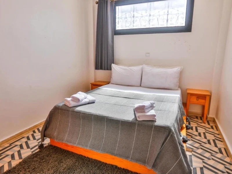 Familienzimmer mit Doppelbett, weißen Kissen, grauer Decke und gefalteten Handtüchern im Moon Surf House in Imsouane.