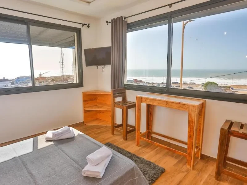 Deluxe-Doppelzimmer im Moon Surf House in Imsouane mit Panoramafenstern mit Blick auf Strand und Ozean.