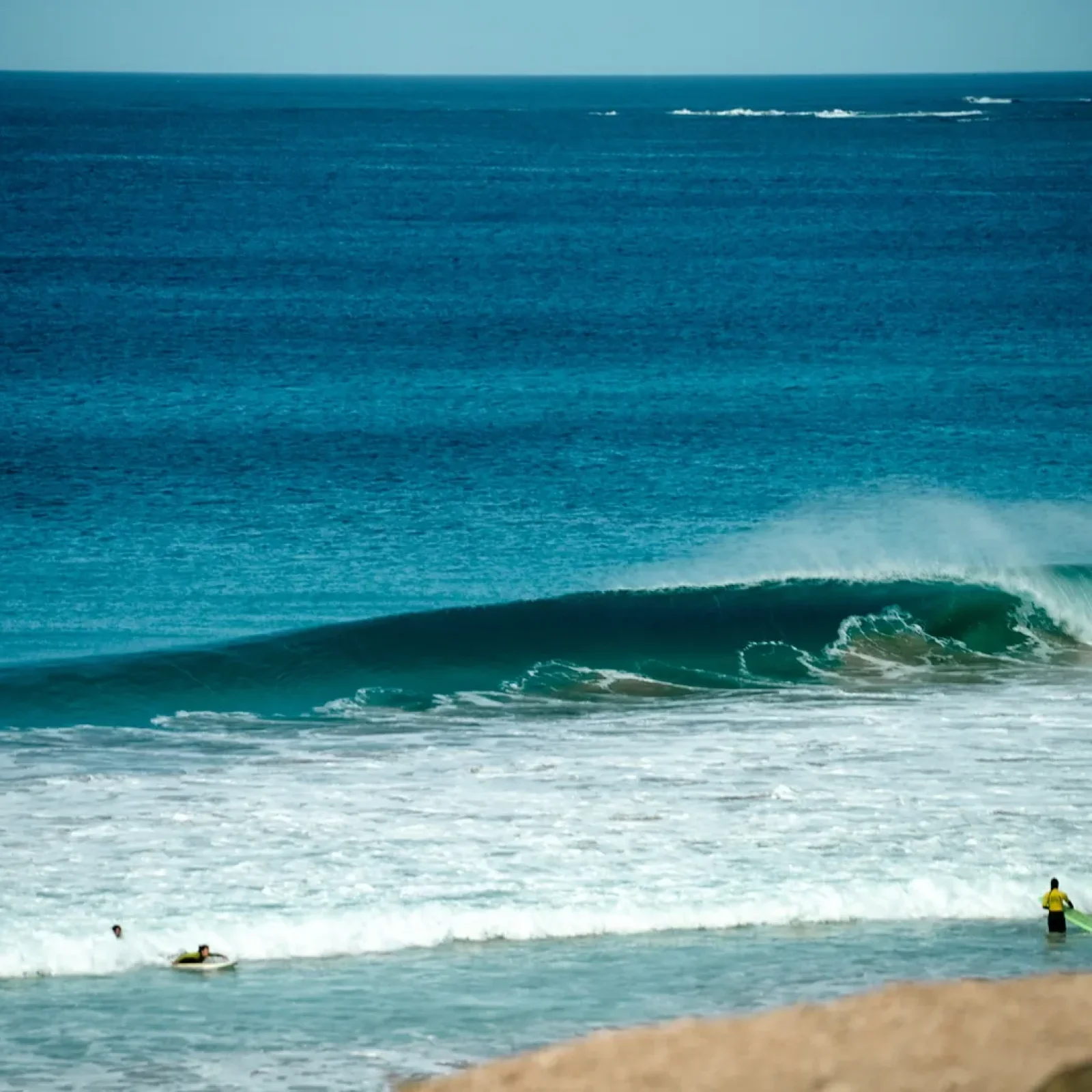 Break de surf avec vagues tubulaires en formation et plusieurs surfeurs dans le line-up à une plage de Fuerteventura.