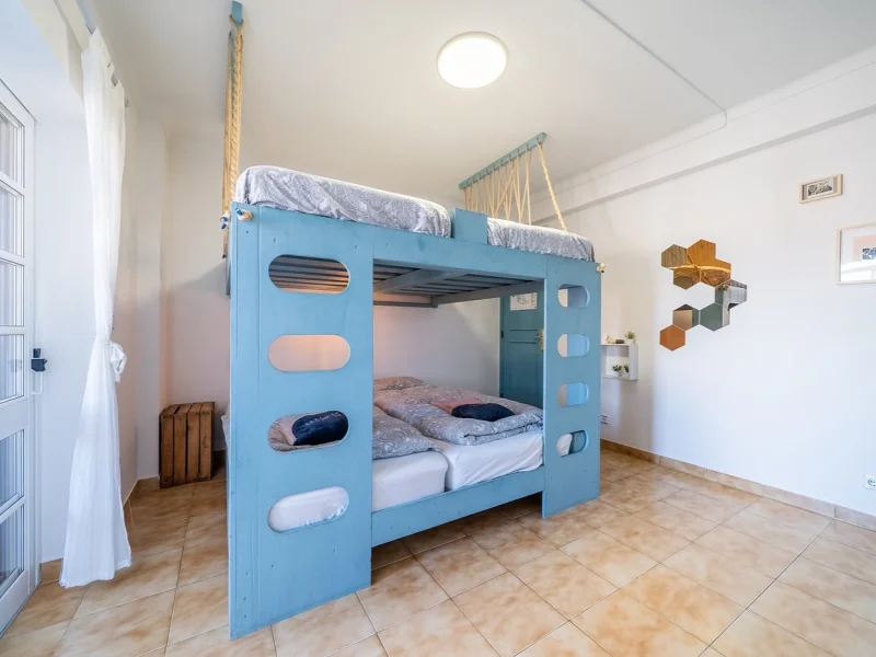 Five Standard room at SURFinn Algarve with dual blue bunk beds, wooden flooring, and minimalist furnishings.