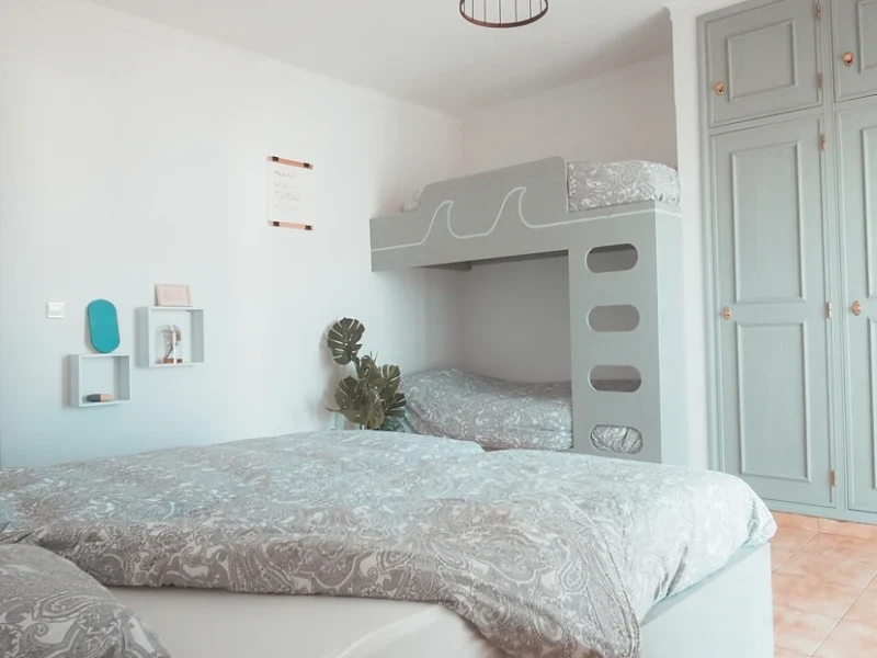 Guest bedroom at SURFinn Algarve featuring a double bed and custom bunk bed unit with ocean wave motif design.
