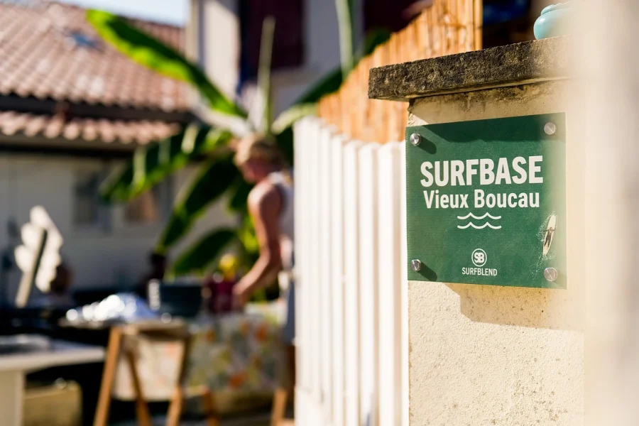 Green sign for Surfbase Vieux Boucau attached to a wooden post at the camp entrance.
