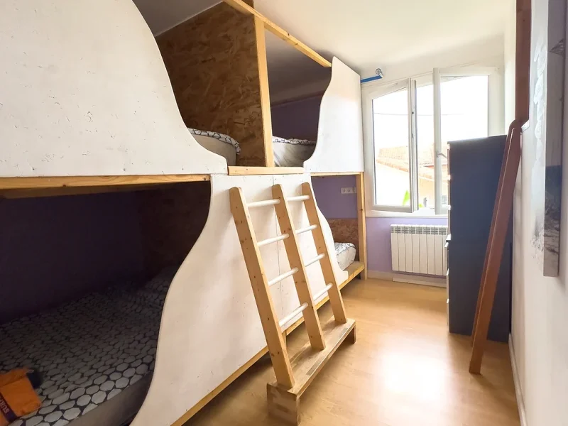 Dorm room at Surfbase Vieux-Boucau featuring multiple wooden bunk beds with ladder access and glass doors leading to terrace.