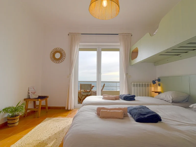 Double Ocean Room with ocean views through glass doors opening to a balcony terrace at SURFinn Figueira da Foz.
