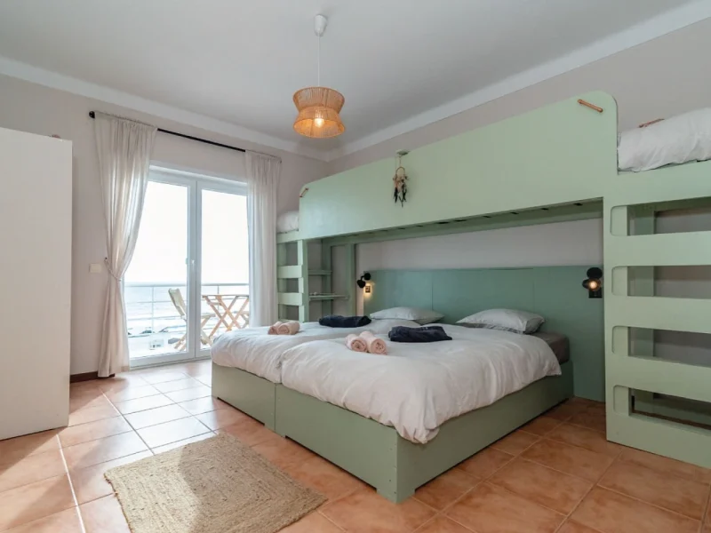 Ocean 4 Room at SURFinn Figueira da Foz with mint green loft bed, ocean view balcony, and coastal furnishings.
