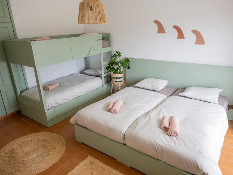 Valley 4 Room with mint green twin bunk bed and single bed, white bedding, and rolled towels at SURFinn Figueira da Foz.