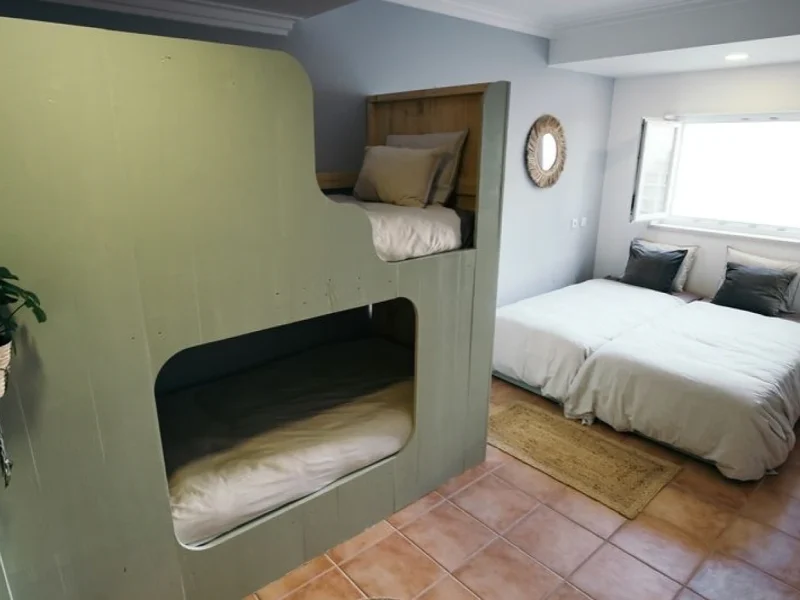 Dorm room with cream and sage-colored bunk bed unit and separate queen bed at SURFinn Figueira da Foz.