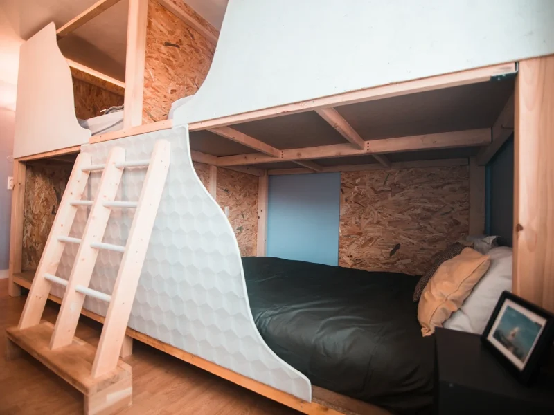 Modern quad room featuring wooden-frame bunk beds with mattresses and a small side window in Vieux-Boucau.