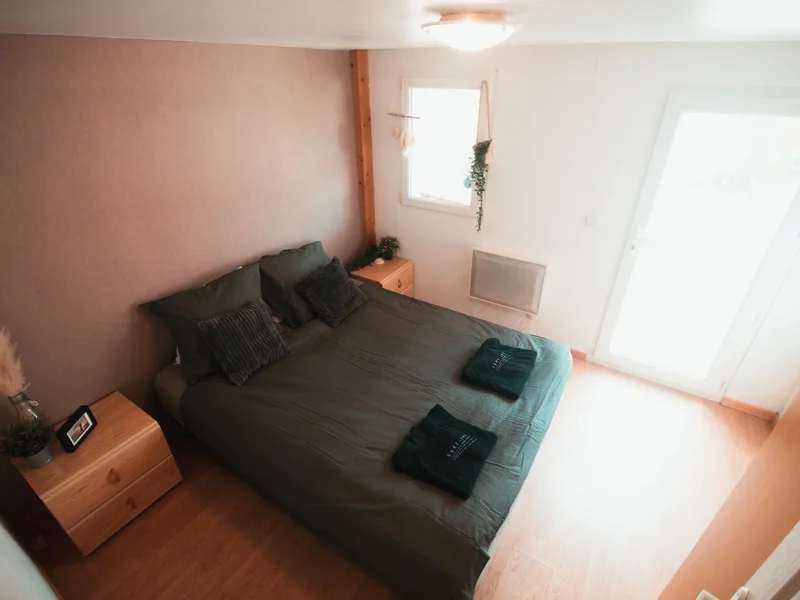 Modern double bedroom with dark bedding, wooden furniture, and pale terracotta-toned accent wall at Surfbase Vieux-Boucau.