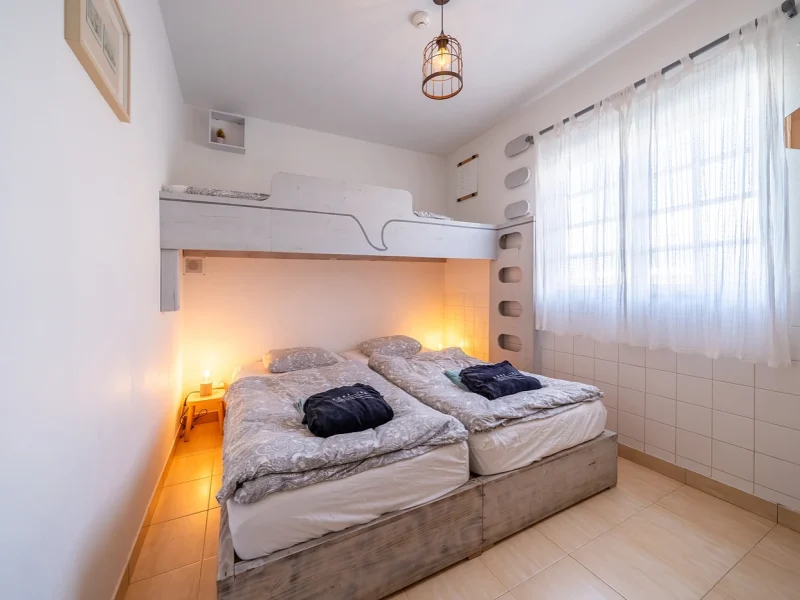 Triple ensuite bedroom at SURFinn Algarve featuring two twin beds with storage bunk above and ambient lighting.
