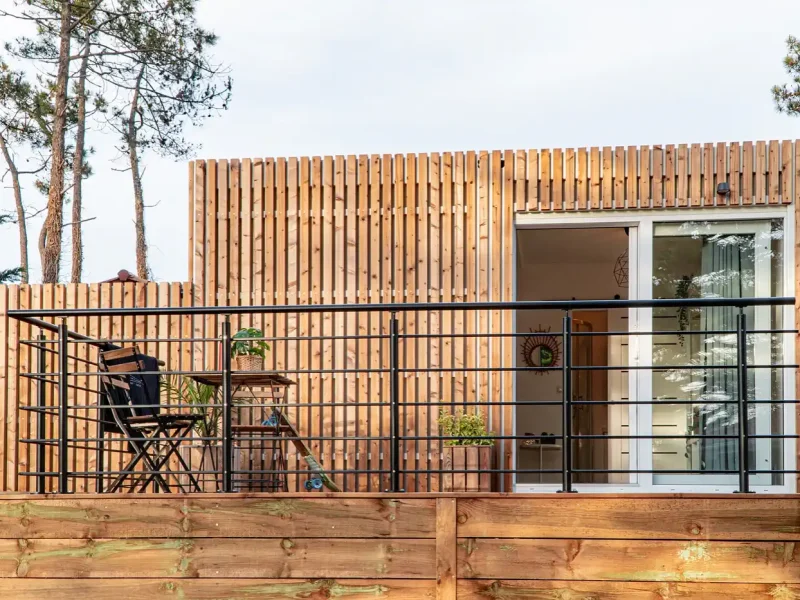 Four Deluxe room terrace at SURFinn Vieux-Boucau featuring wooden slatted exterior cladding, metal railing, and lounge chairs.