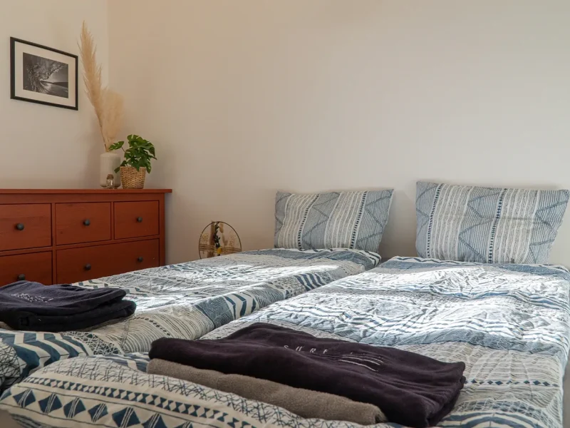 Twin beds with patterned blue and white striped bedding in a Double Deluxe room at SURFinn Vieux-Boucau.