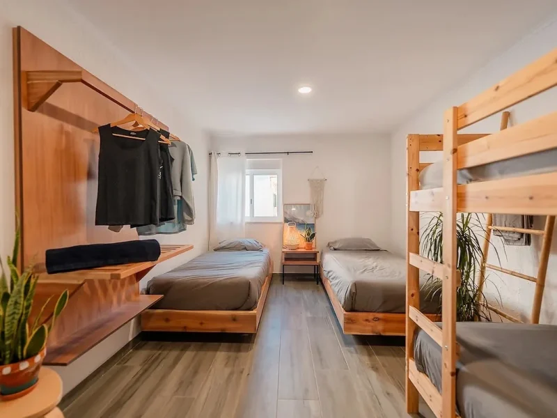 Six Deluxe room at SURFinn Lisbon featuring wooden single beds, built-in storage, and window with natural light.
