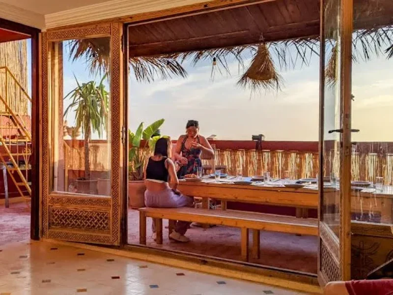 Two people relaxing on a wooden terrace with ocean views at Shaka Surf Morocco in Taghazout, Morocco.