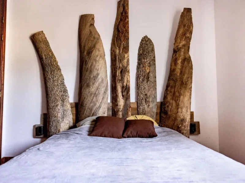 4 Bed Shared Dorm at Stoke Surf House Portugal features a bed with wooden carved headboard in Santa Cruz.