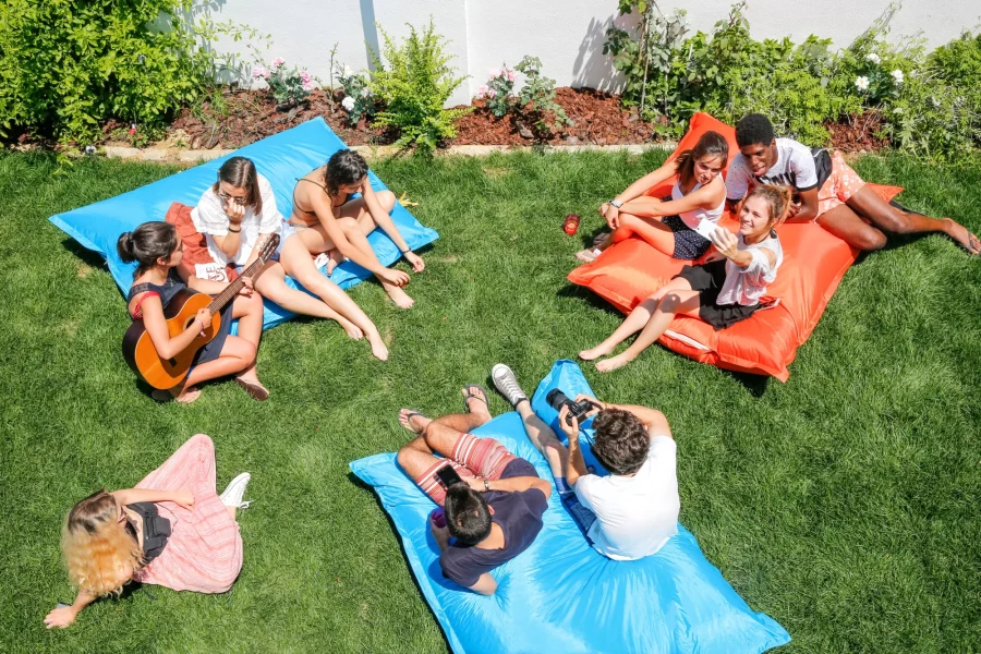 Group of young people enjoying lawn games and socializing on grass at Gota Dagua Junior Surf Camp in Caparica.