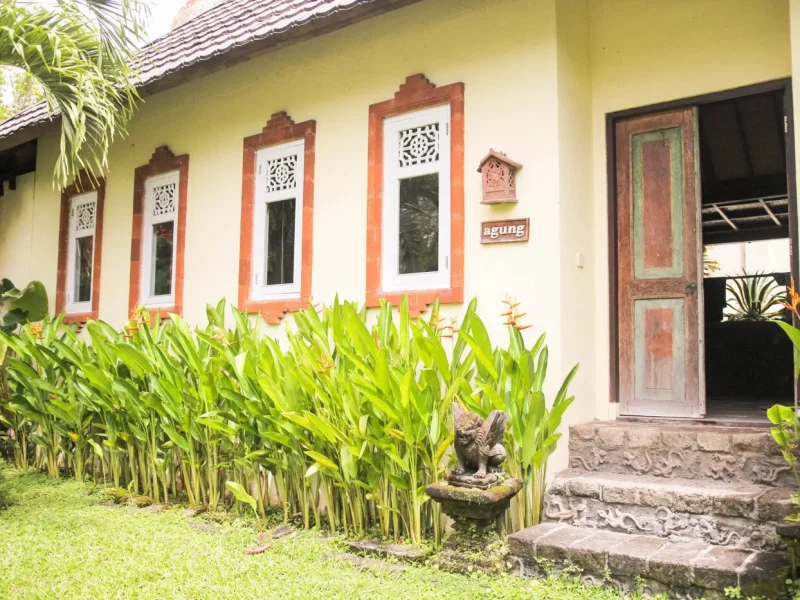 Agung shared room building facade at Mondo Surf Village showing yellow walls with decorative orange window frames and tropical plants.
