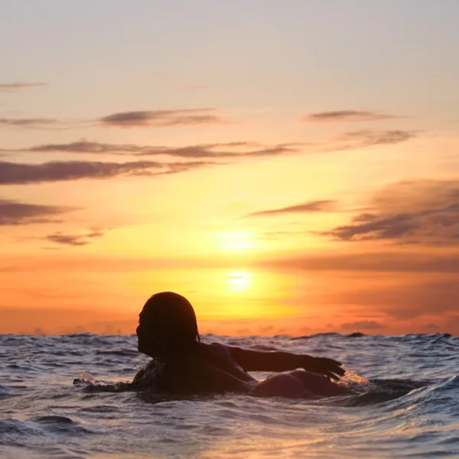 Un surfeur dans l'océan au coucher du soleil à Canggu, Bali.