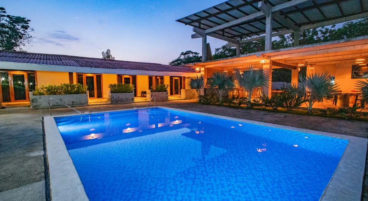 Pool bei Casa Las Flores mit leuchtend blauem Wasser und beleuchteter Holzpergola