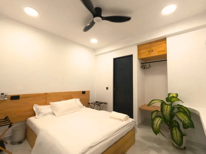 Deluxe Garden Villa bedroom with wooden bed frame, white bedding, ceiling fan, and green plant decor in Kudahuvadhoo.