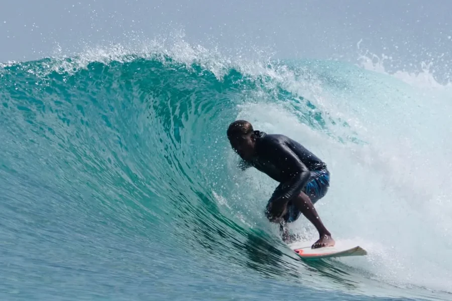 Surfer riding inside a barrel on a turquoise wave in Kudahuvadhoo, Maldives.
