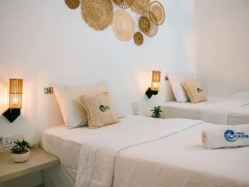 Private double/twin room at The Surfer Beach Camp Weligama featuring white beds with cream pillows and natural fiber wall decoration in Weligama, Sri Lanka.