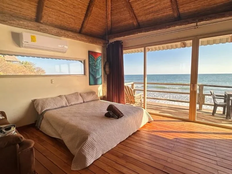 Double Suite at Punta Mango Surf Resort with bed facing oceanfront terrace and beach.