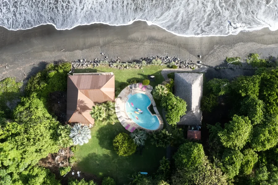 Vue aérienne de Punta Mango Surf Resort montrant la piscine, les espaces verts entretenus et la plage avec vagues qui déferlent au-delà