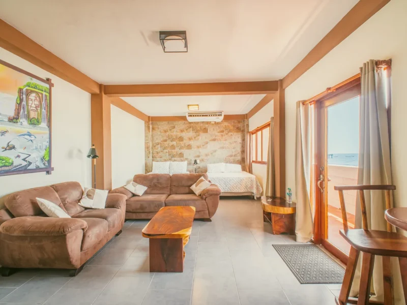 Espace salon Triple Suite avec lit à baldaquin, sièges salon et vue océan depuis le patio front de mer à AST Surf Hotel.