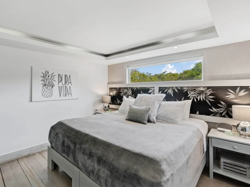 A modern bedroom at Iguana Surf Boutique Hotel in Tamarindo, Costa Rica, featuring a king bed with botanical-patterned headboard and 